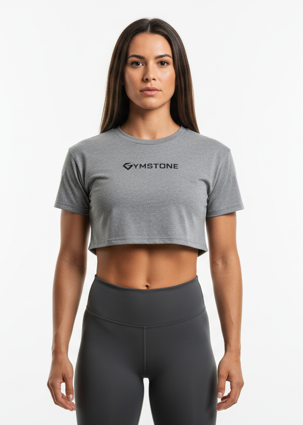 Woman wearing a gray crop top with 'GYMSTONE' logo against a blurred indoor background