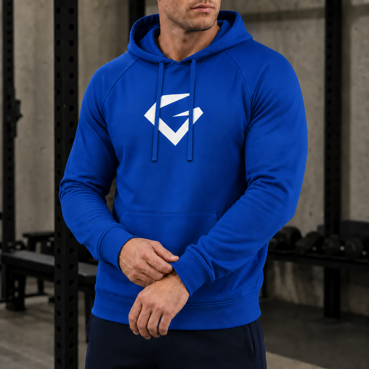 True Royal - A man wearing a royal blue pullover hoodie with a white geometric logo on the chest, standing in a gym environment.